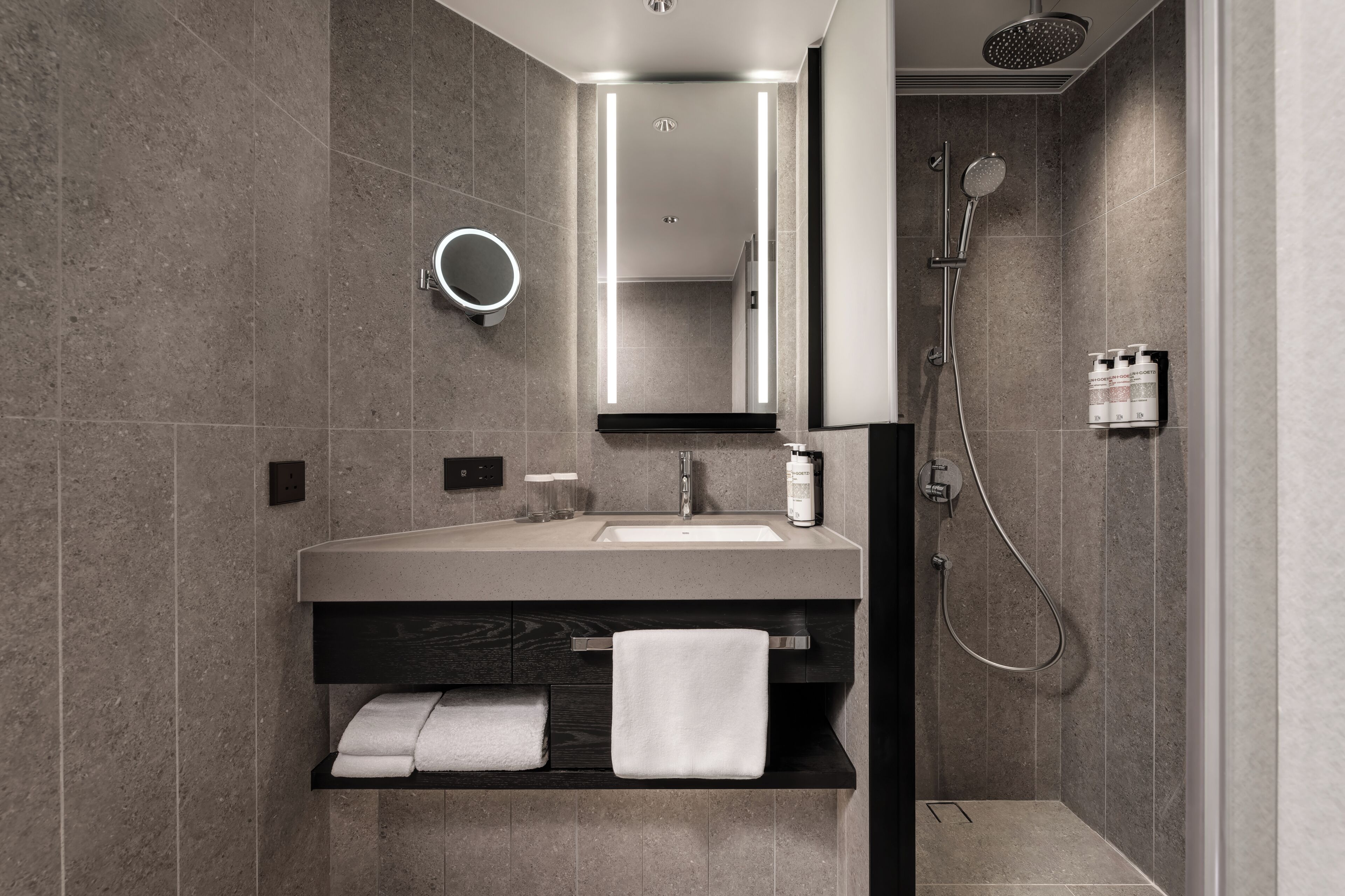 Une salle de bain moderne équipée d’un meuble-lavabo, d’un miroir, d’un porte-serviettes et d’une douche.