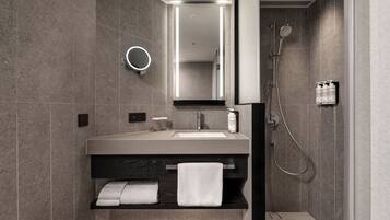 Une salle de bain moderne équipée d’un meuble-lavabo, d’un miroir, d’un porte-serviettes et d’une douche.