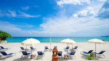 Een privéstrand, ligstoelen aan het strand, parasols, strandlakens