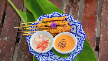 Une assiette de brochettes de satay, accompagnée de deux sauces pour tremper et d’un petit bol de piment.