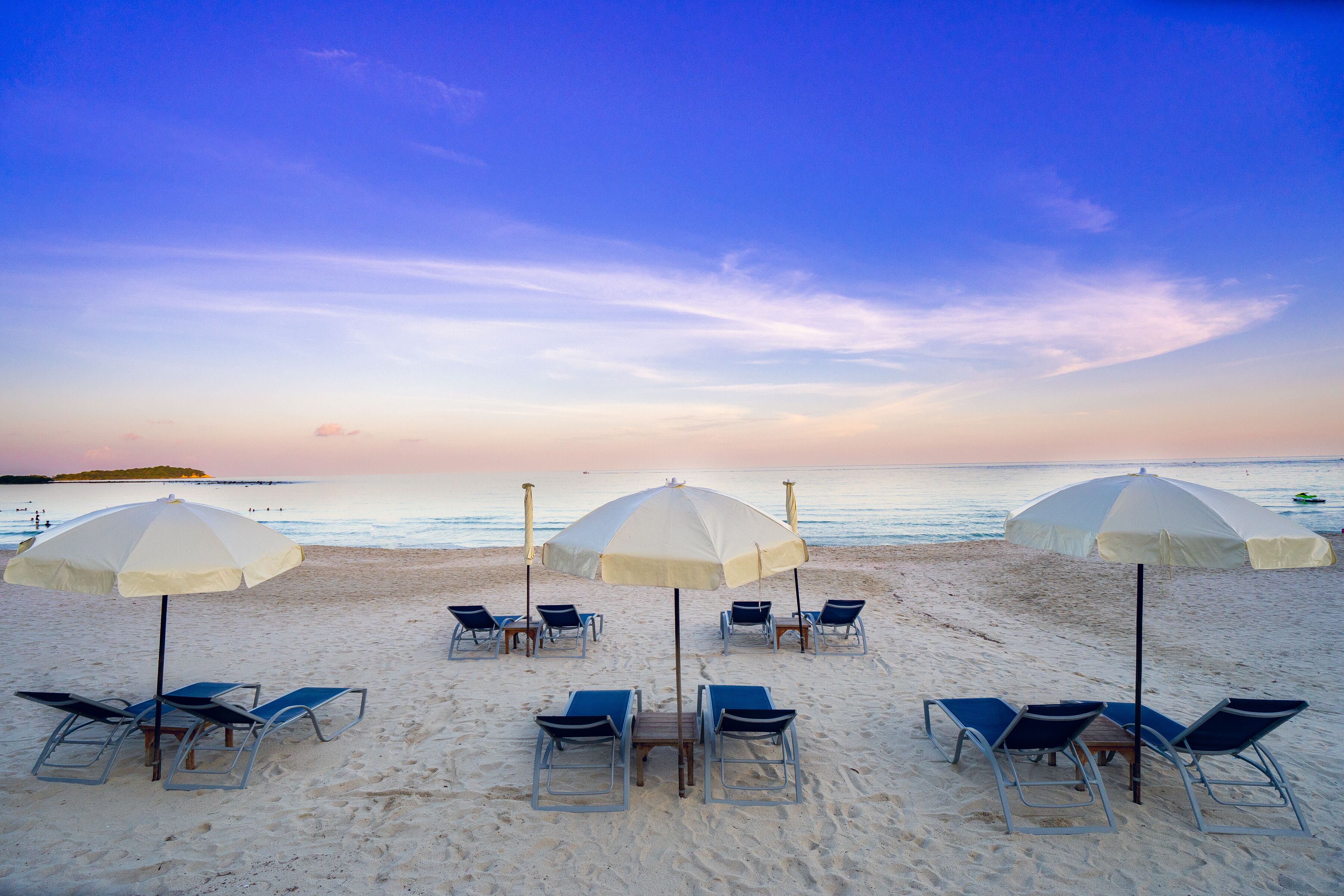A beach with several umbrellas and lounge chairs arranged for sunbathing.