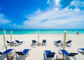 A beach with rows of sun loungers and umbrellas, a clear blue sky, and calm turquoise waters. - Chawengburi Resort (Koh Samui)