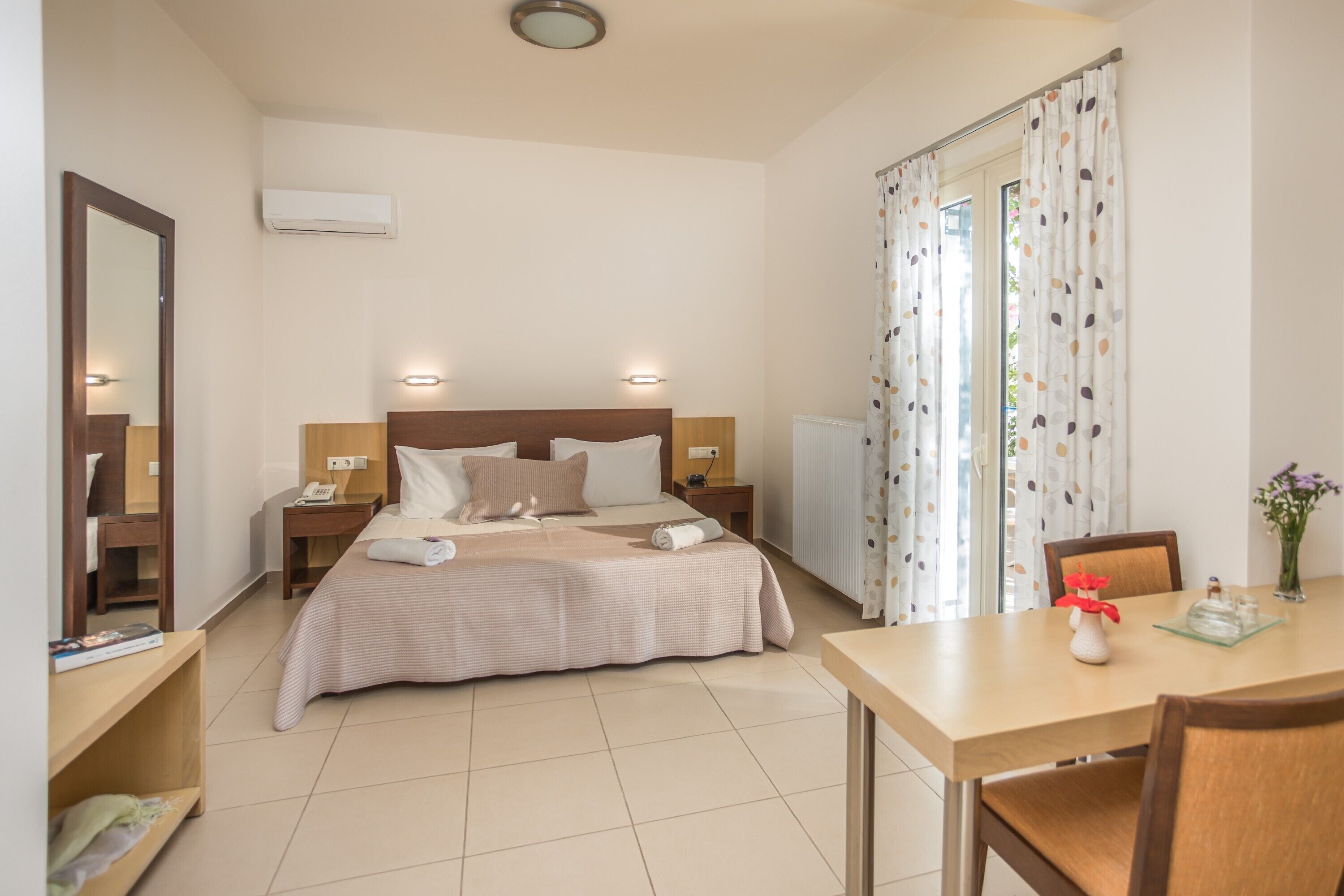 A hotel room with a bed, bedside tables, a desk, and a chair.