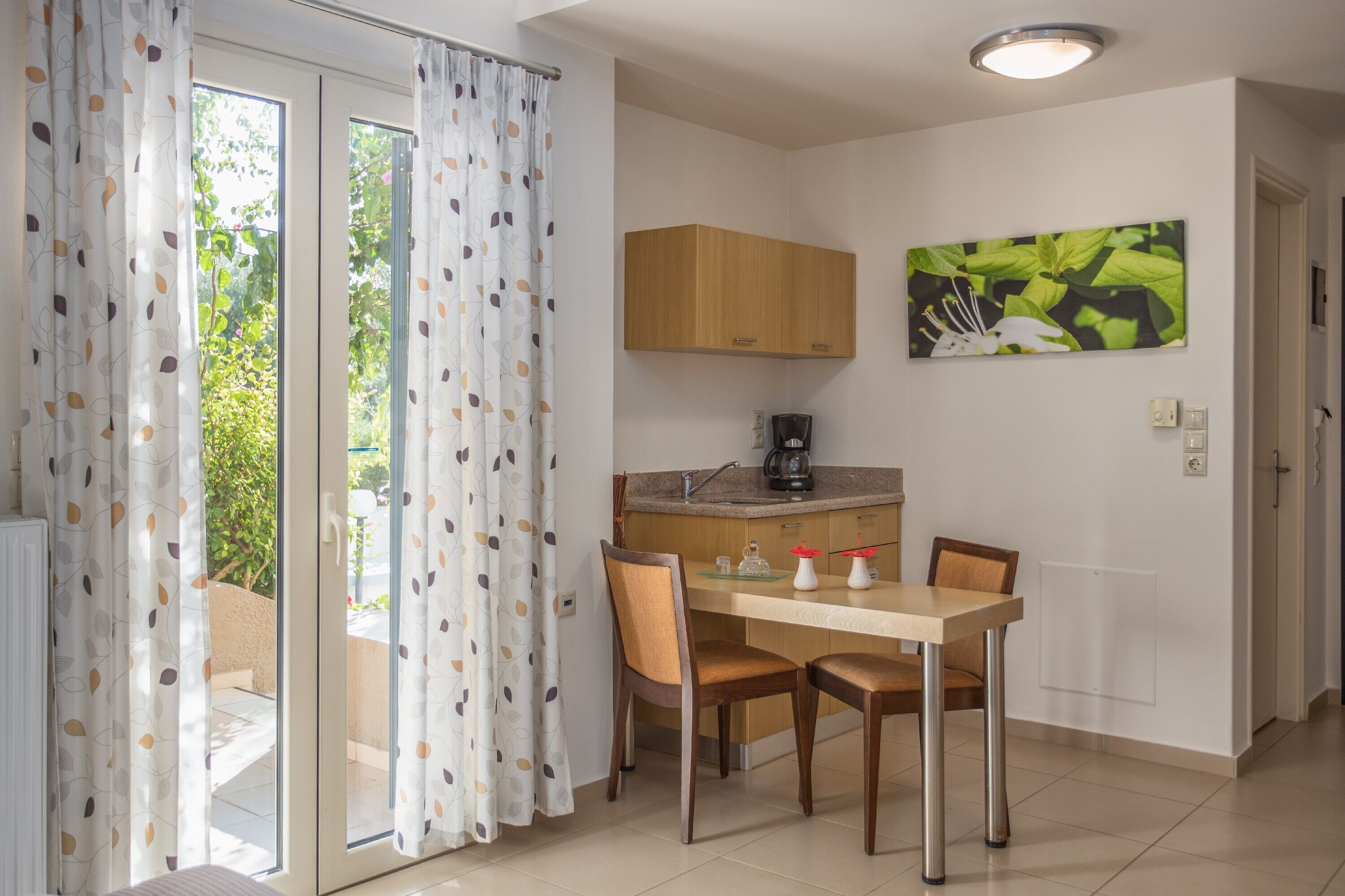 Cozinha moderna com área de refeições, máquina de café e vista pela porta de vidro.