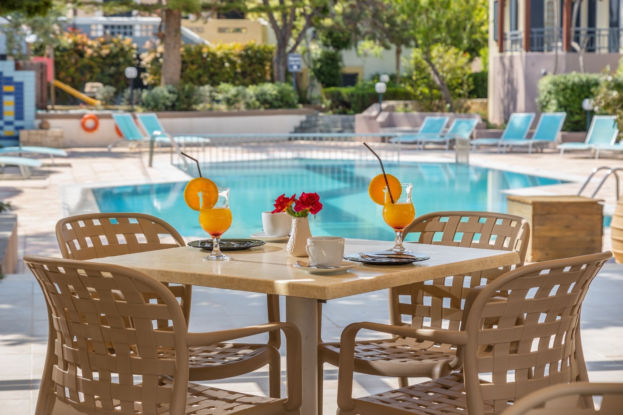 Un espace repas aménagé au bord de la piscine, avec deux tables, des chaises et une vue sur la piscine.