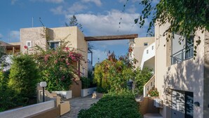 Un patio con un sendero de piedra, rodeado de edificios con paredes color beige y balcones.