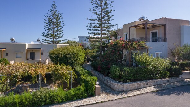Un barrio residencial con edificios modernos, un sendero de piedra y un jardín bien cuidado con árboles y arbustos.