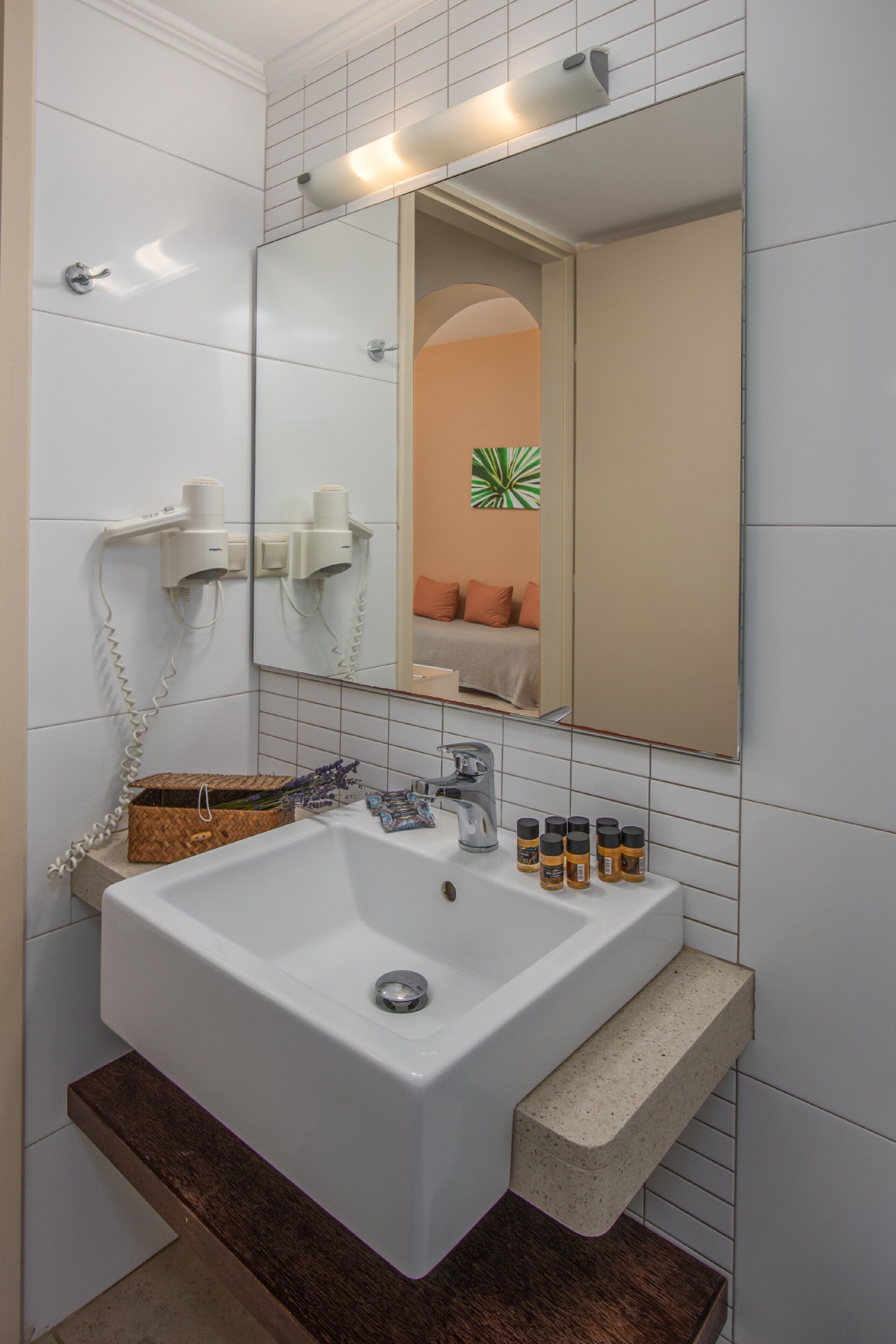 Un baño con un lavamanos blanco, un espejo y un perchero para toallas.