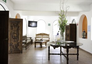 A room with a wooden table, a bench, and a television on the wall. - Hotel Misión Comanjilla (Silao)
