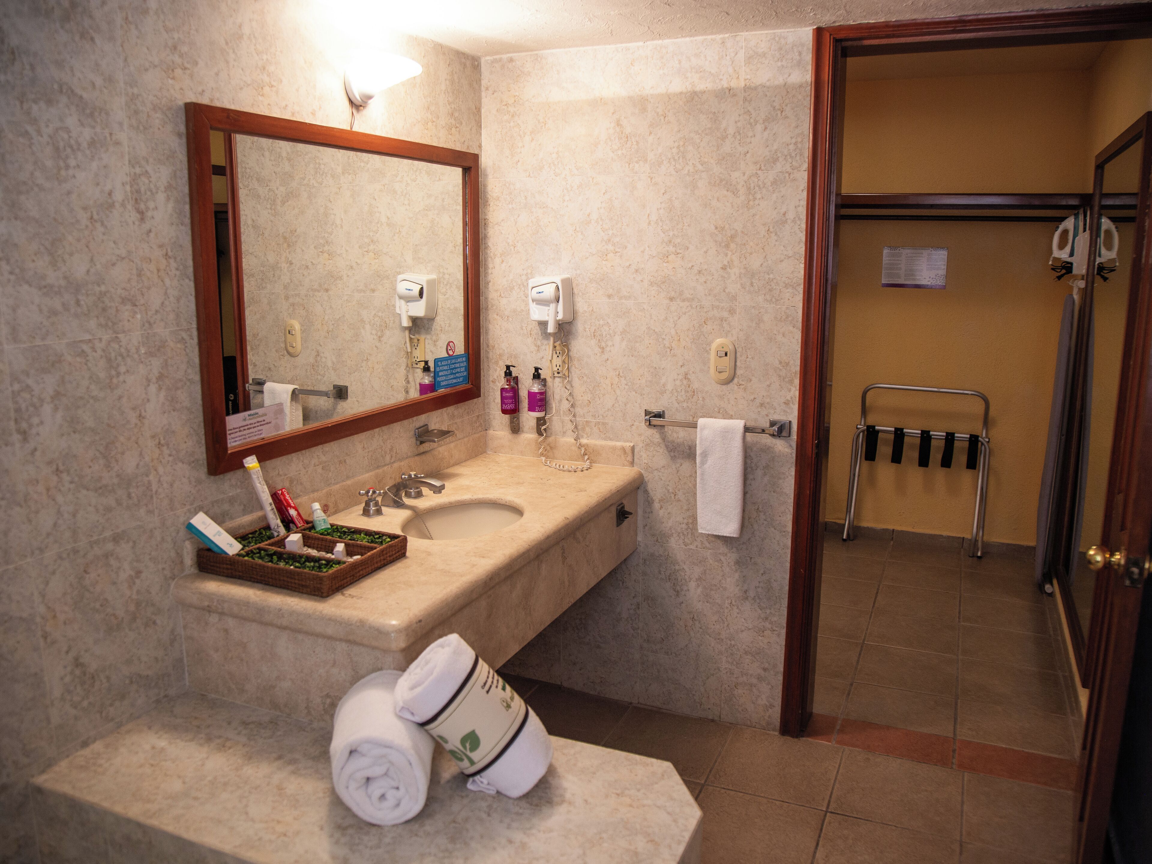 A bathroom with a sink, mirror, towel rack, and a shower area.