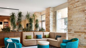 A modern living room with a sectional sofa, two armchairs, a coffee table, and a large window providing natural light. - Hilton Garden Inn Dallas Richardson (Richardson)