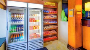 A hotel lobby with a beverage cooler stocked with various drinks, a snack shelf, and a 'The Market' sign.