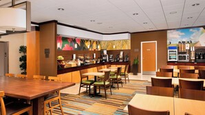 A hotel lobby with a coffee bar, seating area, and a large wooden table.
