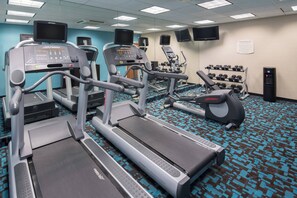 Un centre de remise en forme équipé de tapis de course, de vélos elliptiques et d’un banc de musculation.