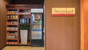 Ein Verkaufsautomat mit dem Aufdruck "The Market", der Snacks, Getränke, eine Mikrowelle und einen Blumentopf enthält.
