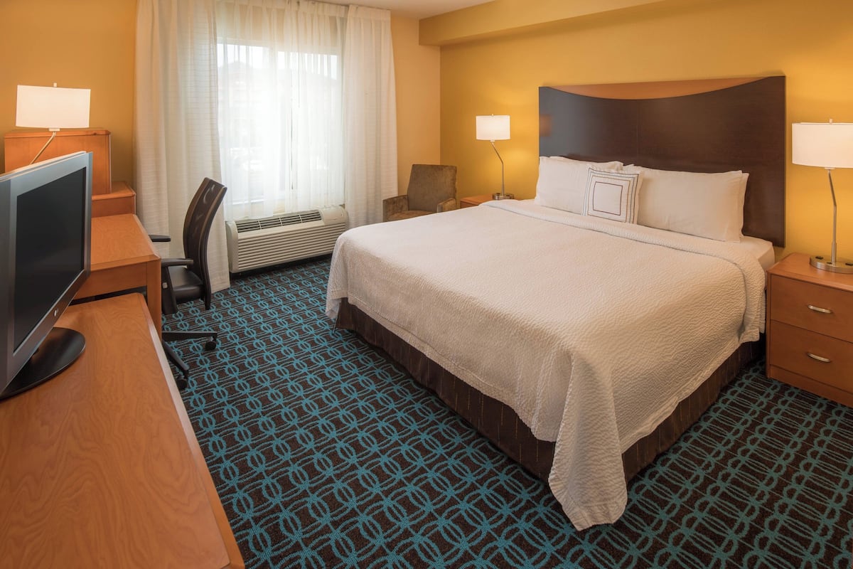 A hotel room with a large bed, a desk with a computer, a chair, and a TV.