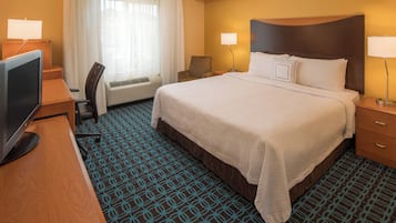 A hotel room with a large bed, a desk with a computer, a chair, and a TV.