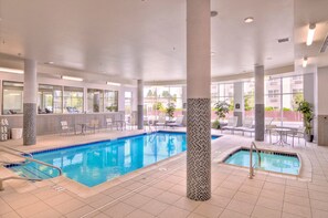 An indoor swimming pool with tiled flooring, lounge chairs, and a view of the outside. - Holiday Inn Express Eugene - Springfield by IHG (Springfield)