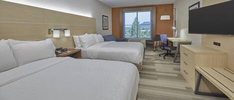 A hotel room with two beds, a desk, a chair, a TV, and a window with a view.