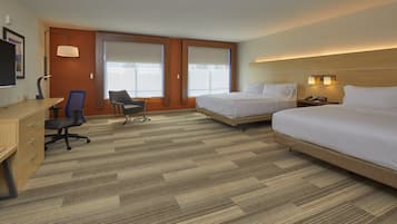 A hotel room with two beds, a desk, a chair, and a TV.