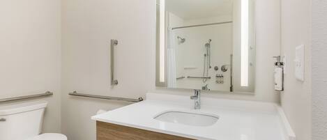 Un baño moderno con lavamanos, espejo y retrete blancos.