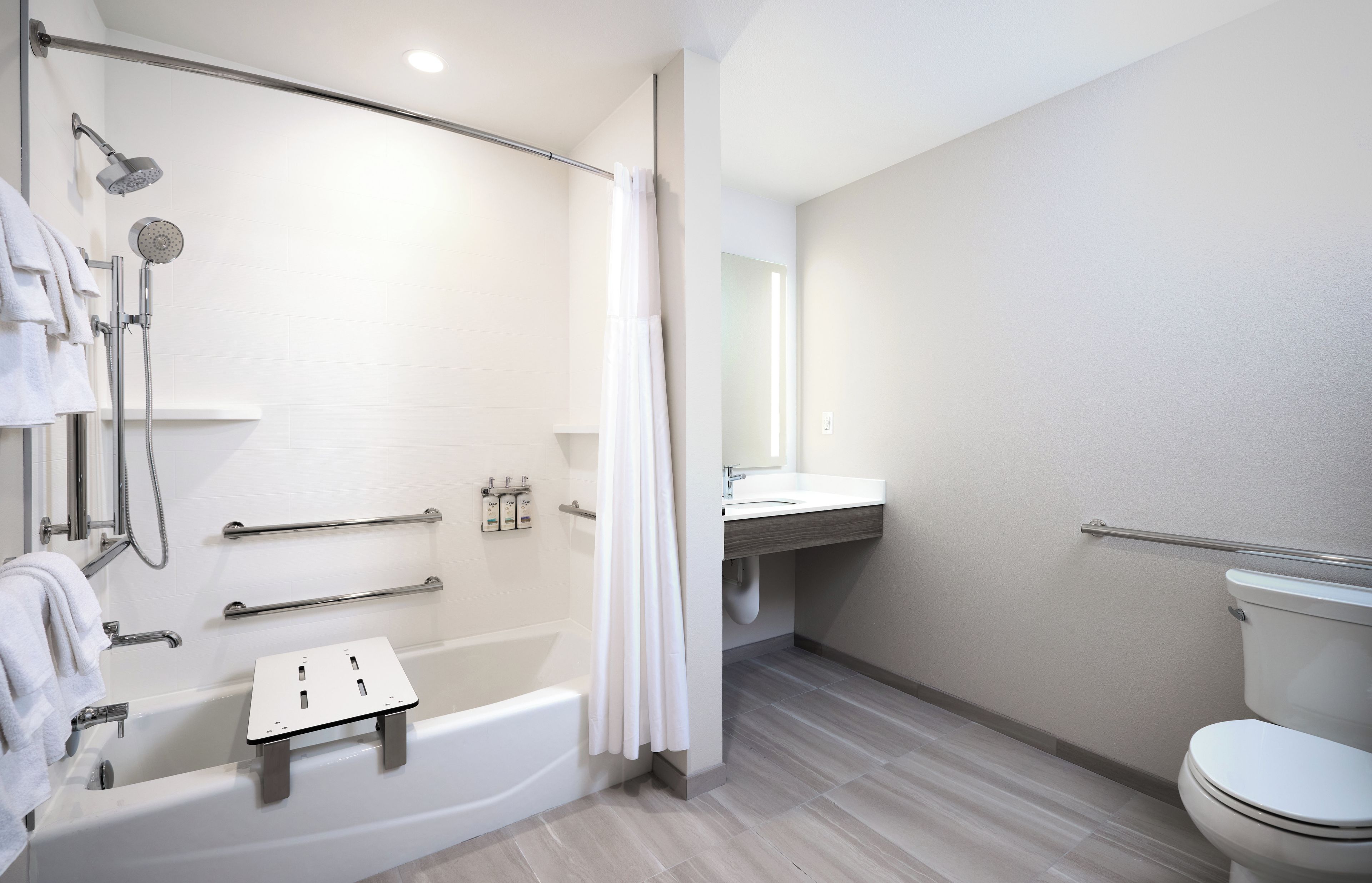 Une salle de bain moderne dotée d’une douche à l’italienne, d’une baignoire, de toilettes et d’un meuble-lavabo avec un miroir.
