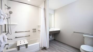 Une salle de bain moderne dotée d’une douche à l’italienne, d’une baignoire, de toilettes et d’un meuble-lavabo avec un miroir.