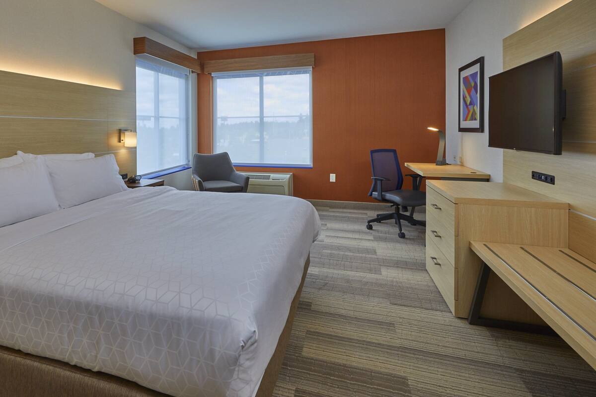 Habitación de hotel con una cama grande, un escritorio, una silla, un televisor y una ventana con vistas.