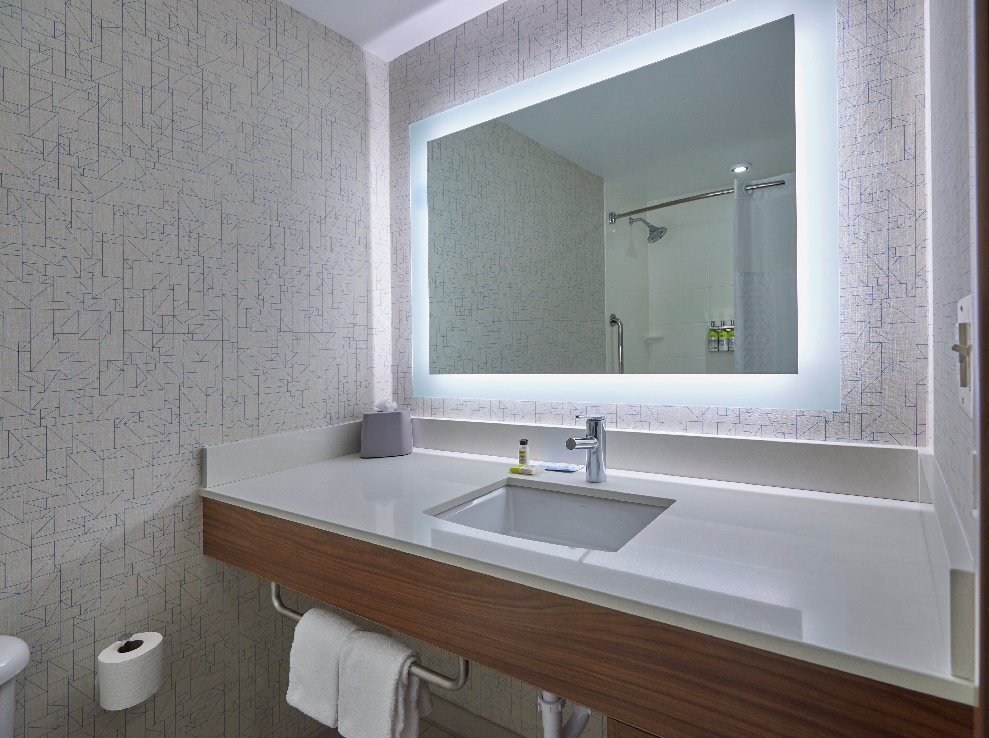 A bathroom with a large mirror, a sink, and a toilet.