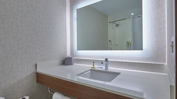 Un baño con un espejo grande, un lavamanos y un inodoro.