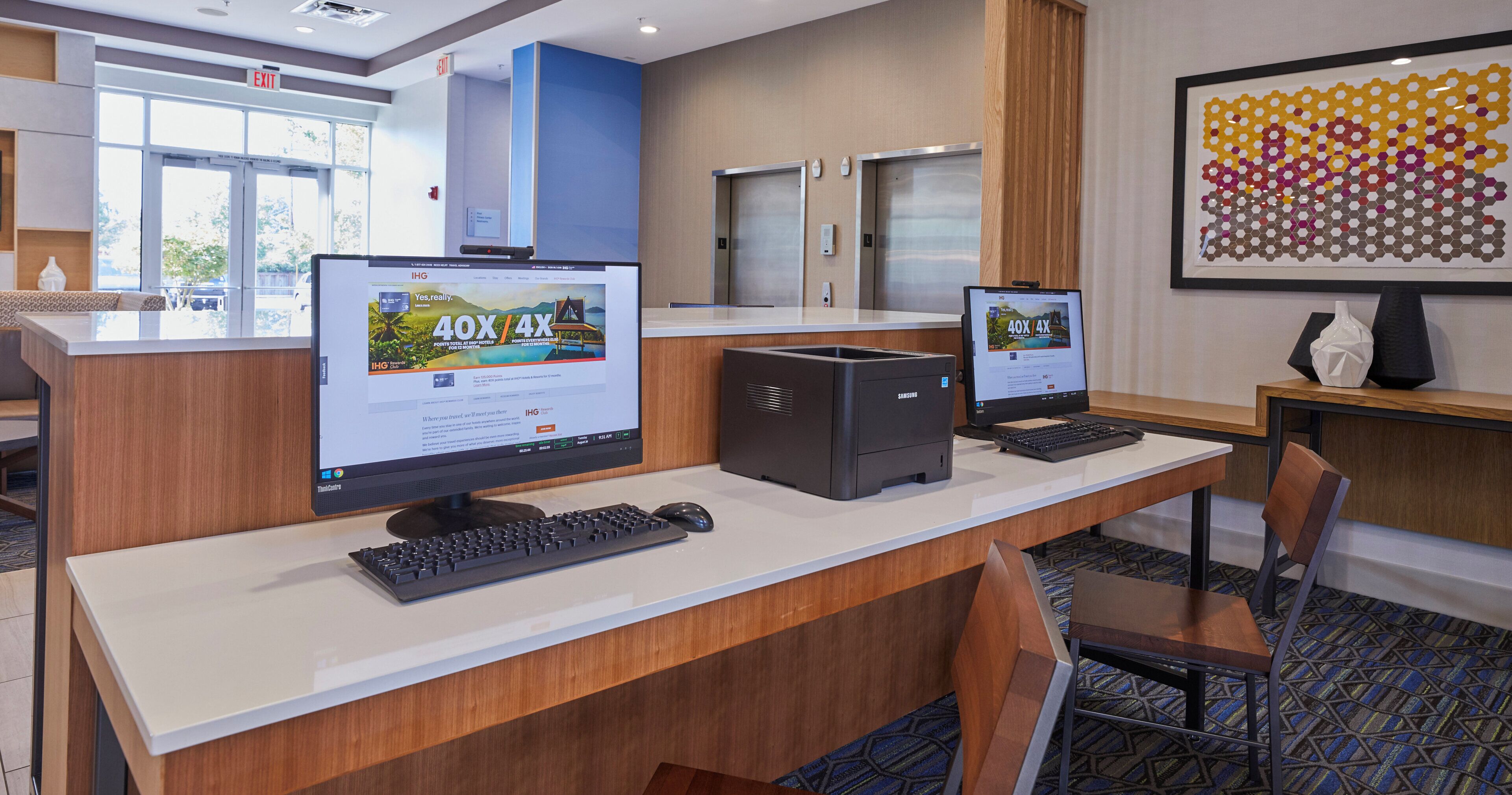 A hotel reception desk with two computer monitors, a keyboard, and a mouse.