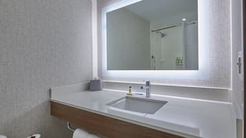 Ein modernes Badezimmer mit großem Spiegel, weißem Waschbecken und Holzwaschtisch.