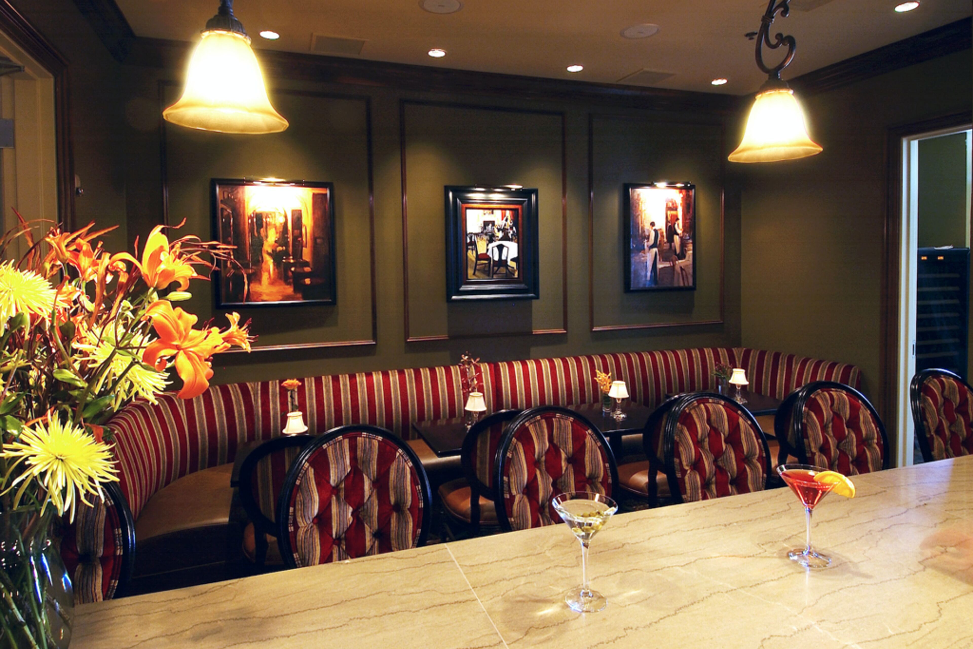 Ein Restaurant mit Marmorbar, gestreifter Sitzbankbestuhung und gerahmten Bildern an der Wand.