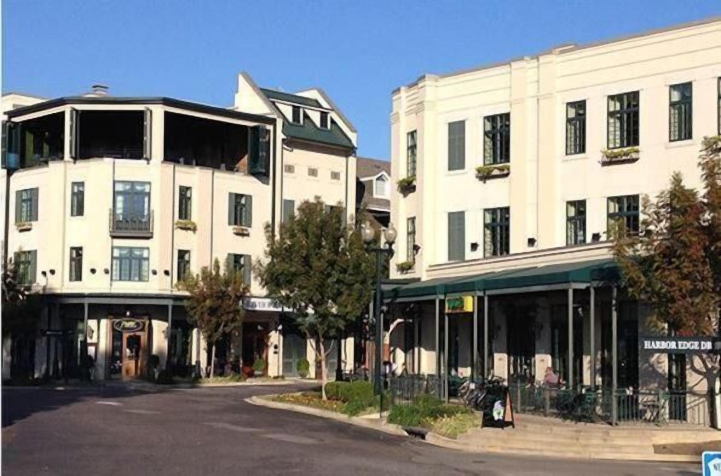 A street view of a building with a corner entrance, a storefront with a sign, and a visible street name sign.