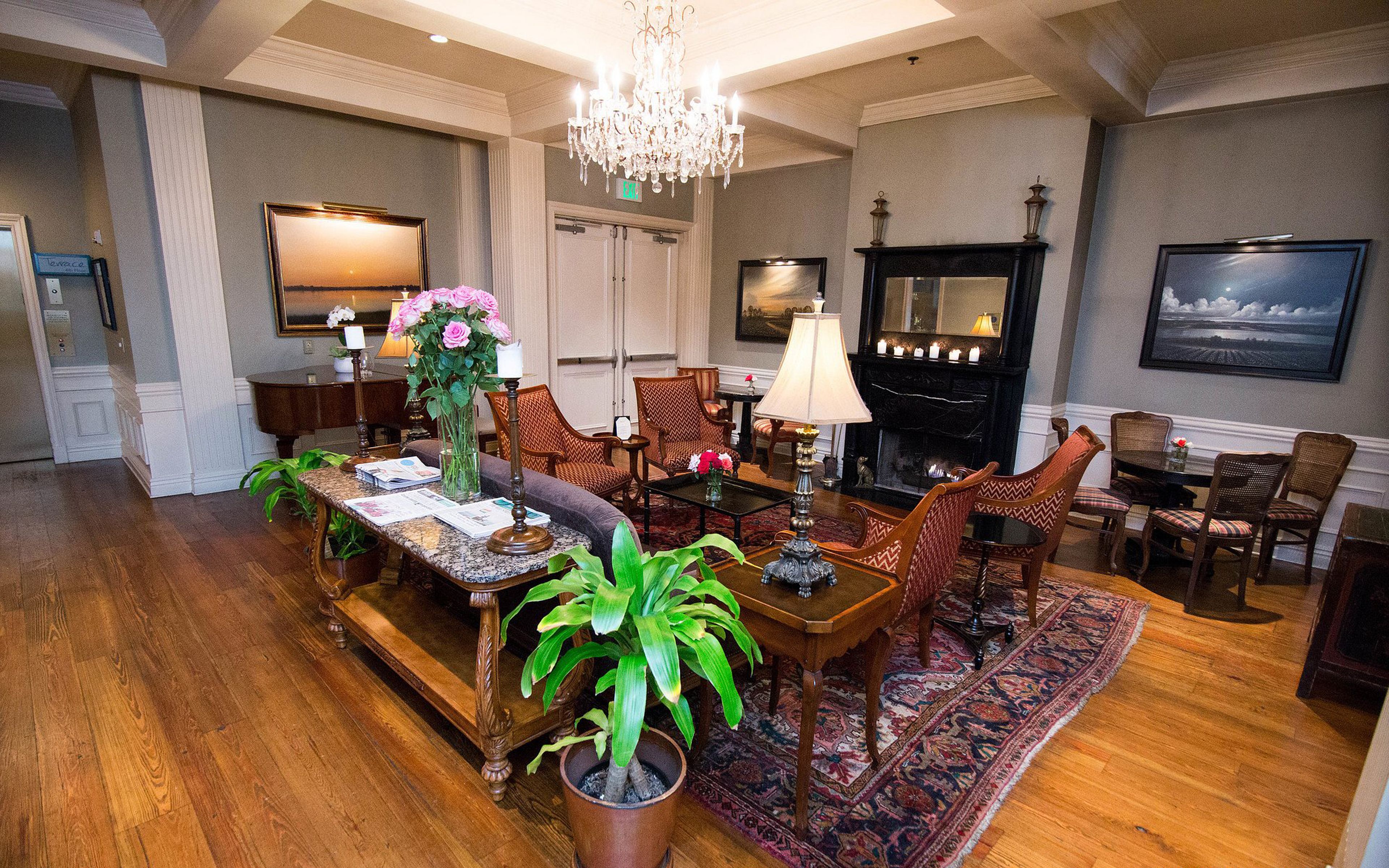 A spacious living room with a fireplace, comfortable seating, and a chandelier.