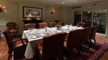 A dining room with a large table set for a meal, surrounded by leather chairs.