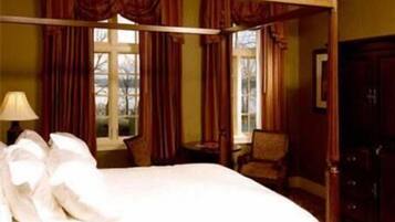 A hotel room with a large bed, a chair, a desk, and a wardrobe.