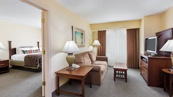 A hotel room with a bed, a sofa, a desk, a television, and a lamp.