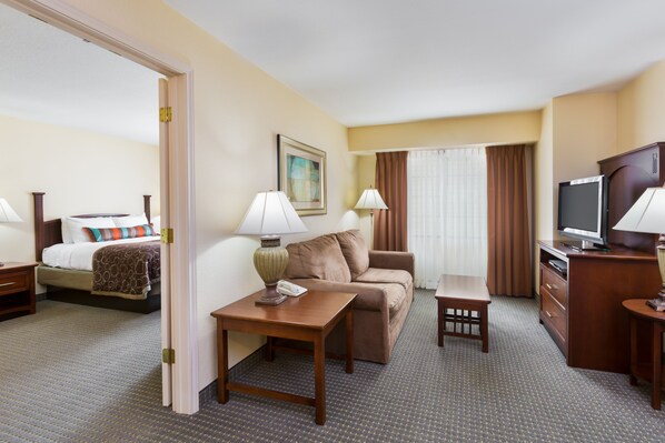 A hotel room with a bed, a sofa, a desk, a television, and a lamp. - Staybridge Suites McAllen by IHG (McAllen)