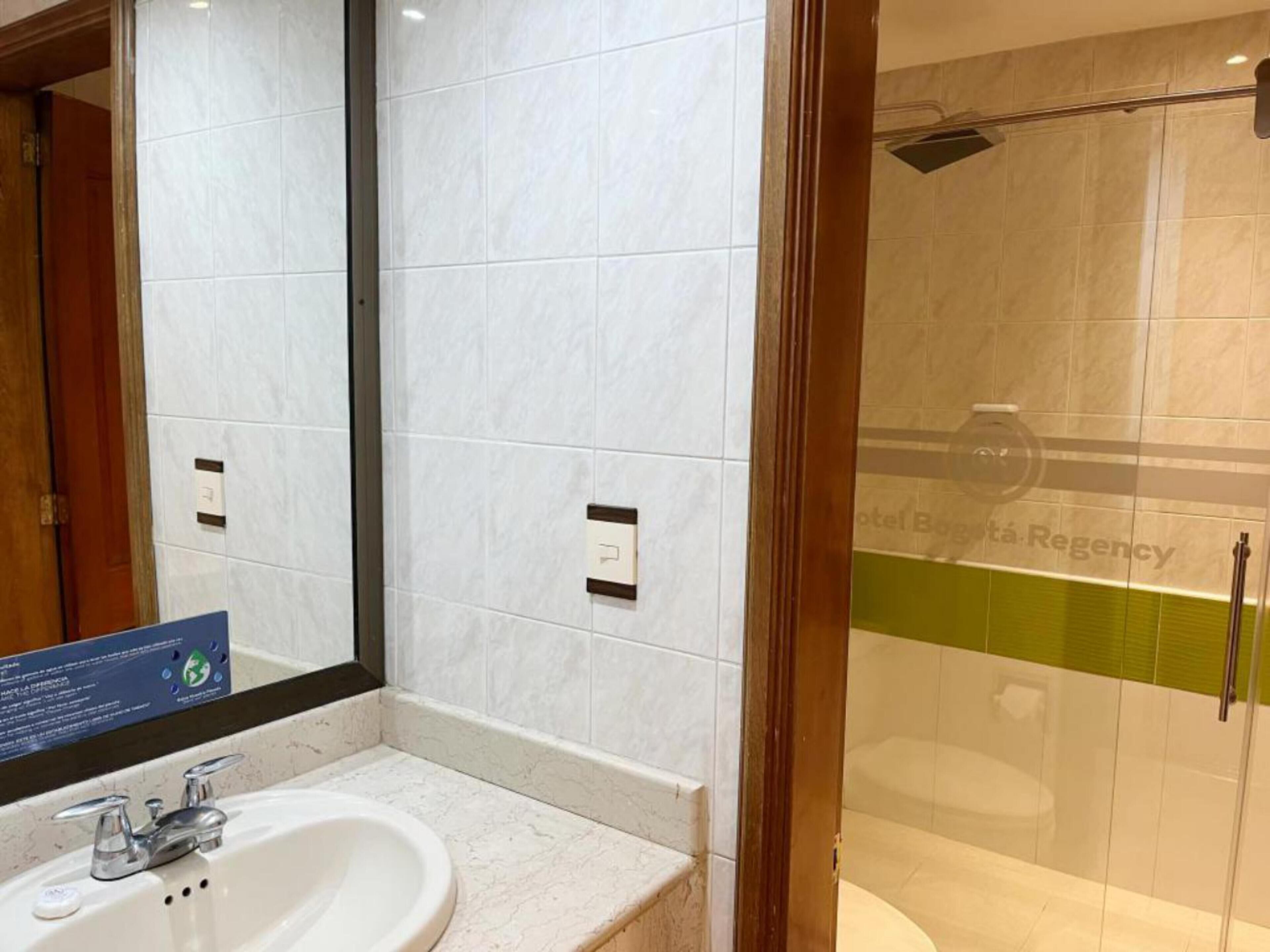 A modern bathroom with a white sink, a mirror, and a glass shower enclosure.