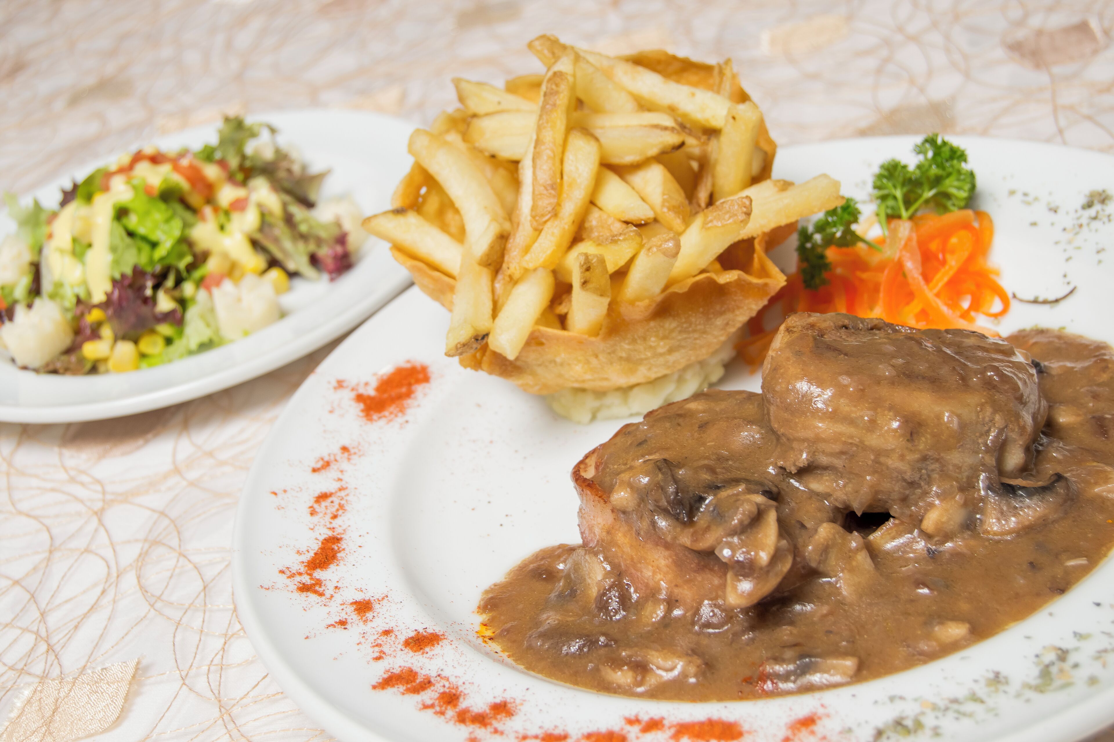 A plate with a meat dish, fries, and a side salad.