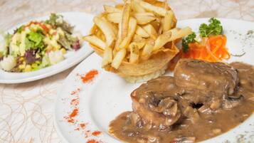 A plate with a meat dish, fries, and a side salad.