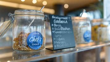Un frasco de vidrio etiquetado como "Chef's Choice" con granola en su interior, colocado en una estantería con un letrero que enumera los ingredientes de la granola.