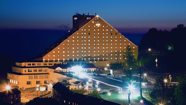 A large hotel with a distinctive triangular roof, multiple floors, and a well-lit parking area. - The Green Park Kartepe (Kartepe)