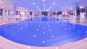 A large indoor swimming pool with clear water, surrounded by lounge chairs and a reception area. - The Green Park Kartepe (Kartepe)