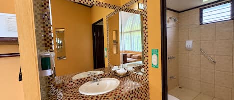 A bathroom with a tiled floor, a sink, a mirror, and a toilet.