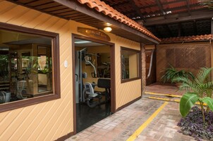 Um centro de atividades físicas com equipamentos de ginástica, uma placa indicando "FITNESS ROOM" e um caminho de tijolos.