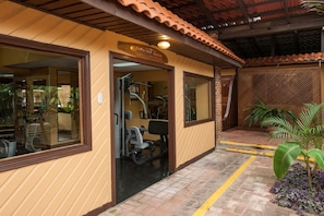 Un gimnasio con equipo de ejercicio, un letrero que dice 'FITNESS ROOM' y un camino de ladrillo.