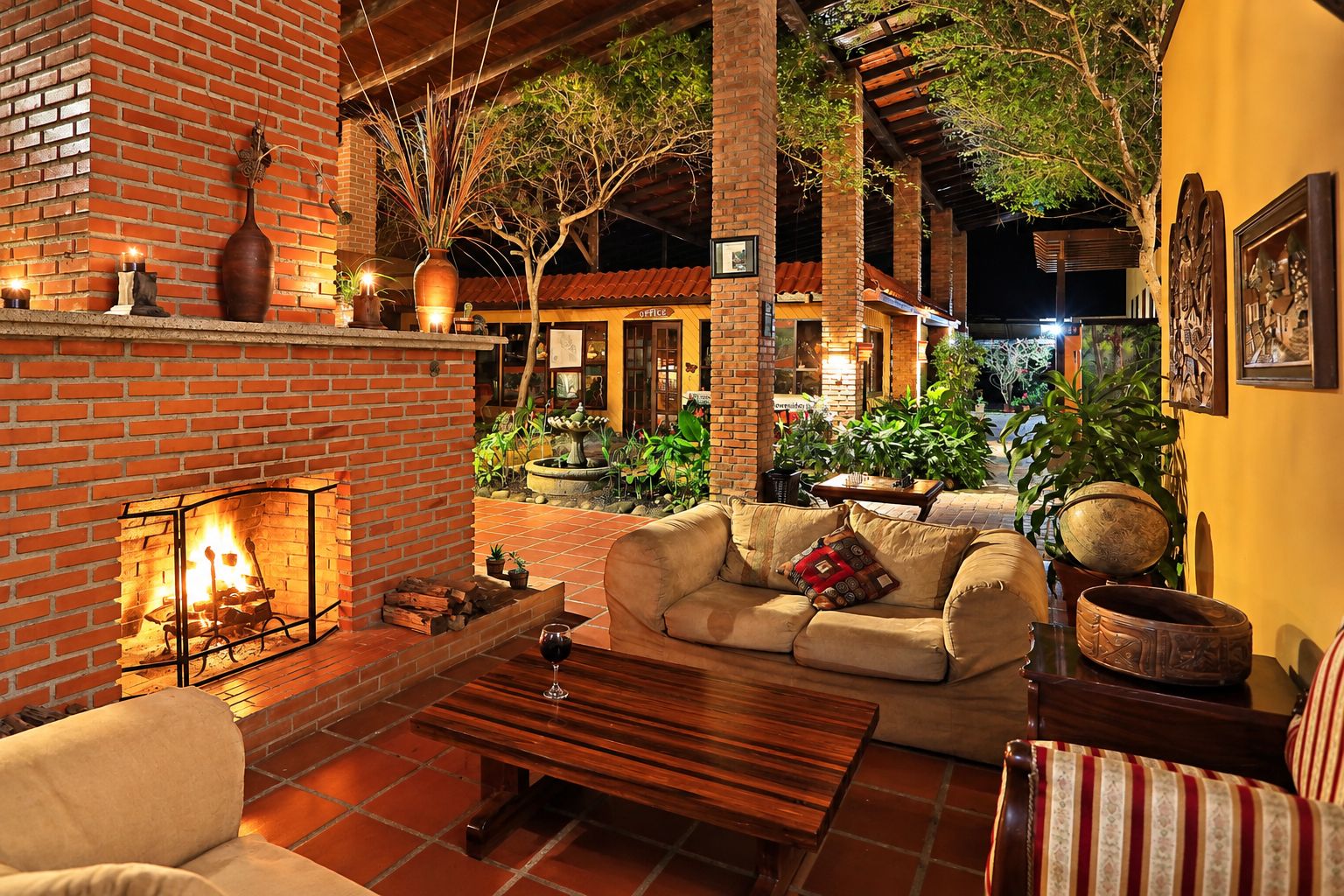 A cozy outdoor seating area with a brick fireplace, a sofa, and a dining table.