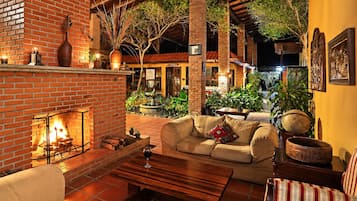A cozy outdoor seating area with a brick fireplace, a sofa, and a dining table.
